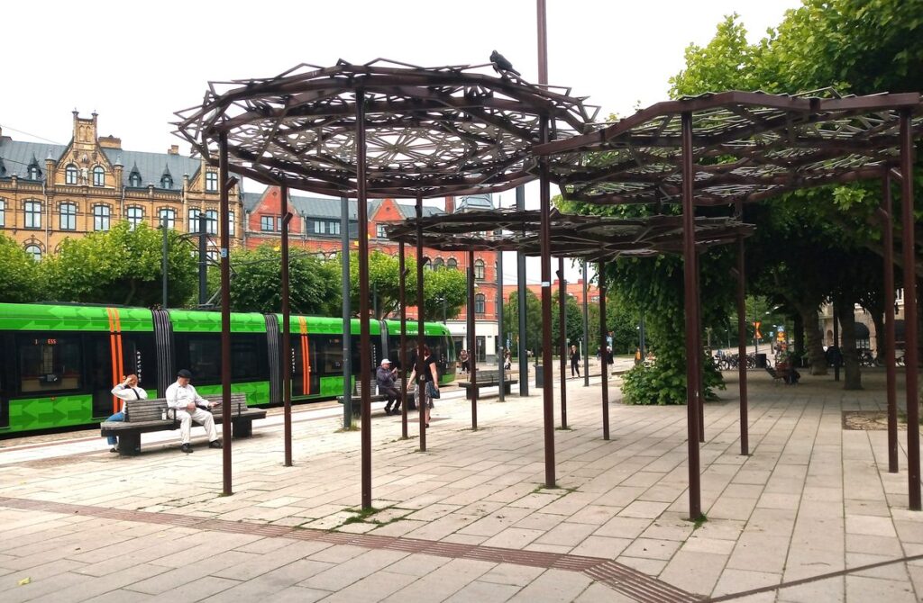 Clemenstorget i Lund med spårvagn och sittplatser under träden